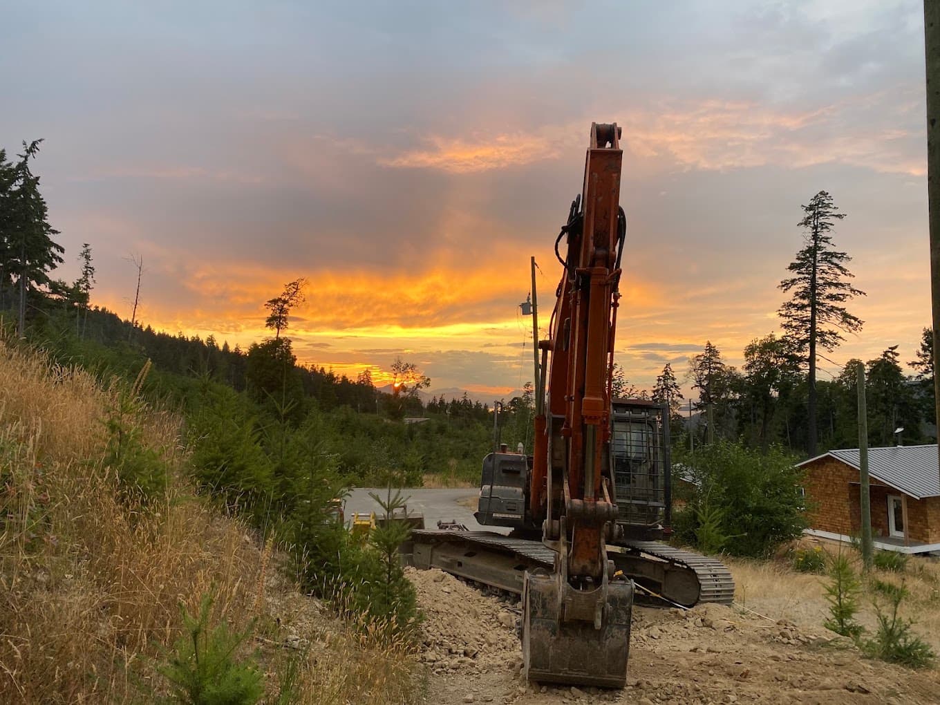 An excavator parked on a newly finished pad on Salt Spring Island at sunset
