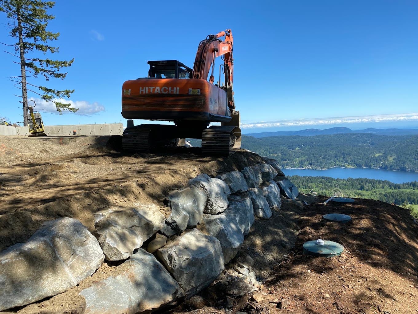 A finished septic field with riser lids set into fresh soil, above a lake on Salt Spring Island